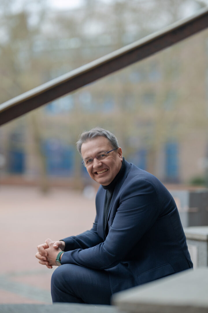 Man in a suit smiling on a bench.