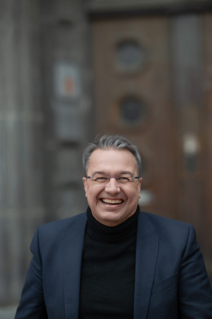 Smiling man in front of a blurred background.
